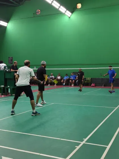A wide view of the court during a doubles rally, showing the engagement of both players and spectators.