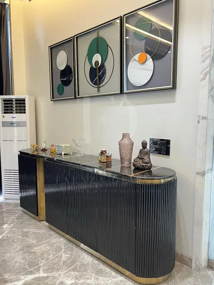 Another angle of the modern black and gold console, showing how it elegantly anchors the wall space beneath a triptych of contemporary art.