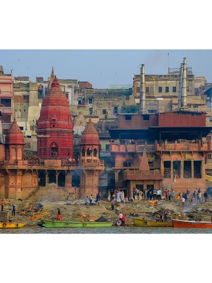 A wide view of Manikarnika Ghat in Varanasi, the primary cremation ghat, showing the constant flow of life and death by the Ganges.