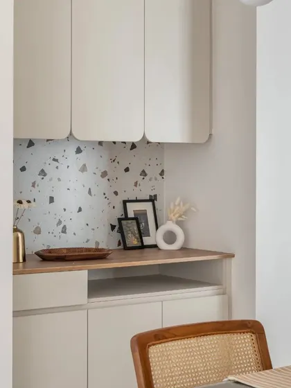 A view of the compact and stylish crockery unit, with a terrazzo backsplash adding a playful pattern against the neutral cabinets.