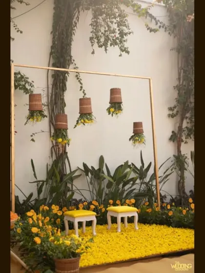 A simple, elegant setup for an intimate Haldi, using a frame, hanging baskets, and a carpet of yellow flowers. This shows that even smaller events can be beautifully designed.