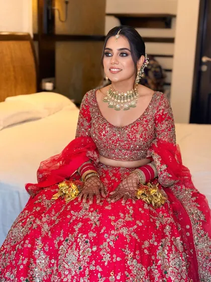 The full look of the bride in her red lehenga. The updo keeps the hair off her neck and shoulders, highlighting the beautiful design of her blouse and jewelry.