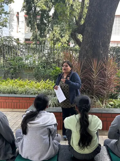 An outdoor lesson in progress, where a teacher uses the natural surroundings to explain a concept to her students.