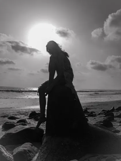 A striking silhouette against the setting sun. This black and white image is dramatic and artistic, telling a story with light and shadow.