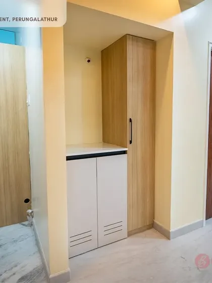 A dedicated laundry unit in the Perungalathur apartment, with custom cabinets to conceal the washing machine and provide extra storage.