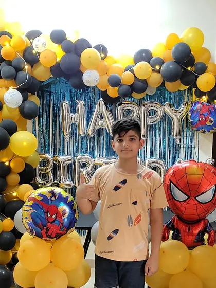 The complete setup for the yellow and black Spiderman party, featuring a "Happy Birthday" foil banner and character balloons.