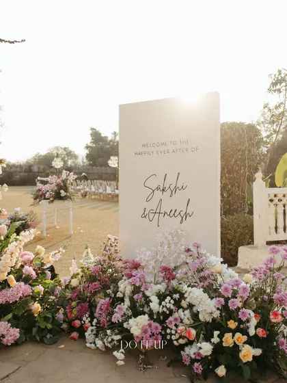 A custom welcome sign for the couple, nestled in a bed of pastel flowers. These personal touches are essential to making the wedding feel unique and telling the couple's story.