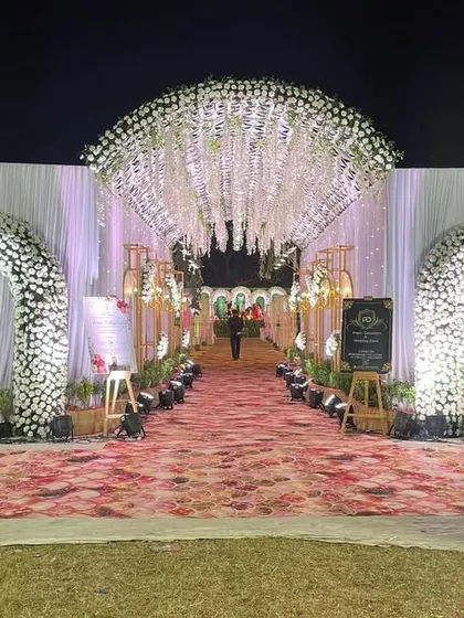 A dreamy floral entrance for an outdoor wedding. We created multiple arches covered in white flowers leading into a tunnel with a ceiling of hanging wisteria, making for a magical walk-in experience.