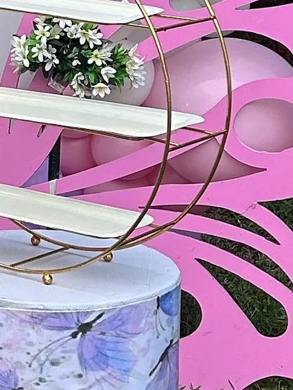 A close-up of a gold tiered dessert stand placed on a butterfly-themed plinth. The details matter, from the large props down to the serveware.