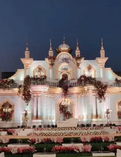 The palace-themed wedding stage at dusk, with the lights creating a warm, inviting glow against the evening sky.