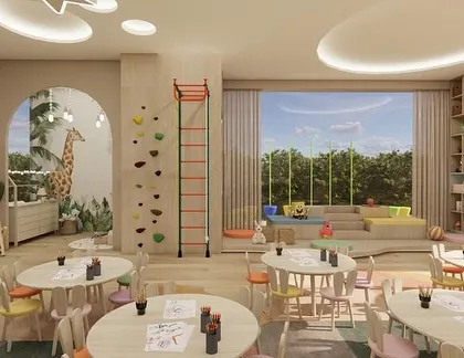 A wider view of the crèche, showing the activity tables, climbing wall, and a reading nook with a large window. The design creates a second home where imaginations can soar.