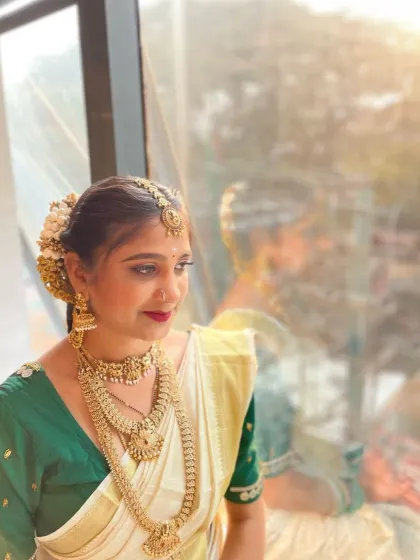 A beautiful portrait of a South Indian bride, showcasing the traditional white and gold saree paired with temple jewelry. The makeup is kept soft and radiant to complement the natural beauty.