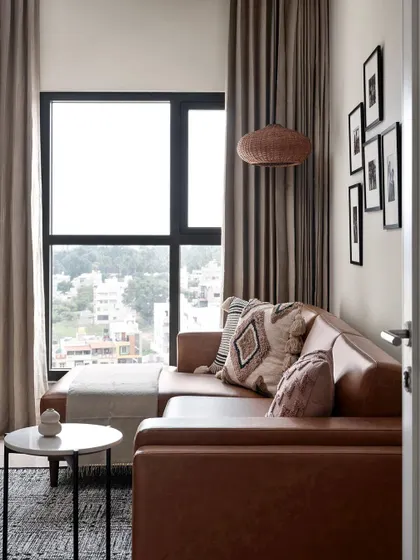 A cozy corner in the same compact home, featuring a comfortable tan leather sofa. The space is designed to be refined and calming, perfect for a small apartment.