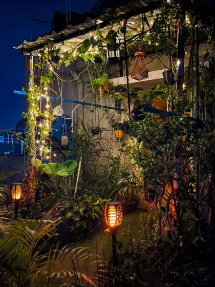 A duplicate image that emphasizes the lush, vibrant feel of the garden post-rain, with the solar torches adding a fiery contrast to the cool night air.
