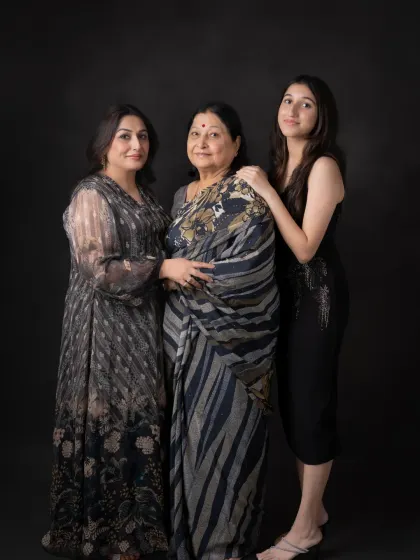 A full-length portrait of three generations of beautiful women. This shot captures their strong family bond and individual grace against a classic black studio background.