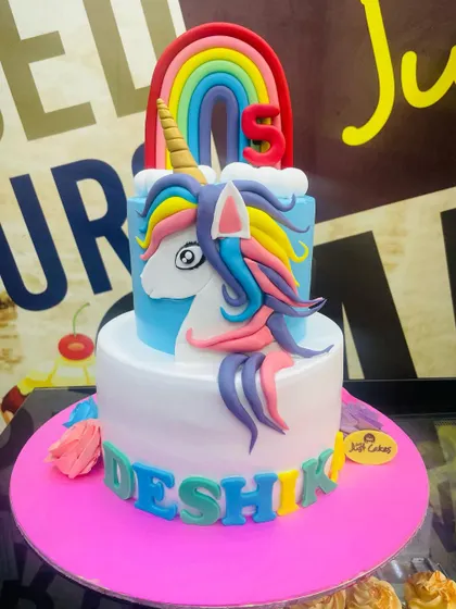 A magical 4kg two-tiered unicorn cake with a rainbow on top and a beautifully sculpted fondant unicorn.