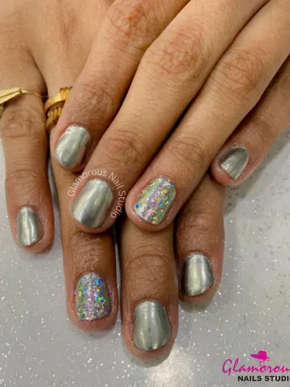 A sleek metallic silver polish is given a fun twist with accent nails featuring a vibrant, multi-colored holographic glitter. This design is perfect for parties and celebrations.