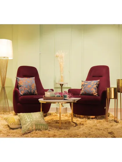 Two maroon armchairs create an intimate conversation nook, complete with a marble-top coffee table and elegant floor lamp.