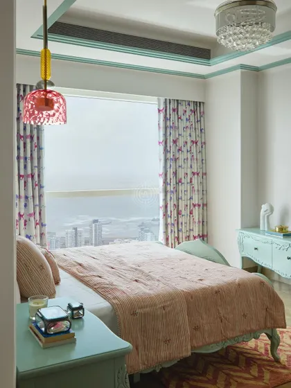 The bedroom offers a beautiful view of the sea, with a color palette of soft pinks and greens that creates a calm and cheerful atmosphere. The furniture has classic, carved details.