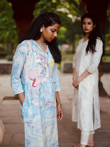 This shot creates a sense of depth and context, with the marbled kurta in the foreground and another outfit in the background. It’s an effective way to display multiple pieces from a collection in a single, cohesive lifestyle image.