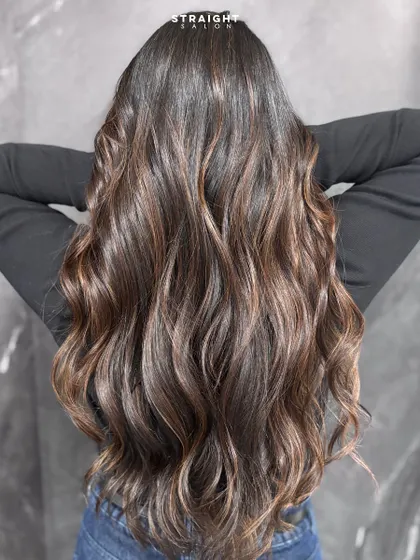 The ultimate glow-up with subtle caramel highlights and soft waves. This look is all about enhancing natural brunette hair with warmth and texture.