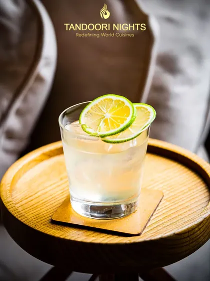 Raise a glass to good vibes. A simple, elegant cocktail garnished with lime wheels, served on a wooden tray, perfect for a sophisticated corporate gathering.
