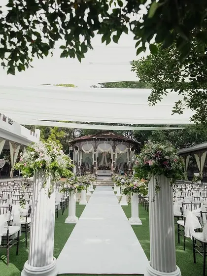 The main lawn set up for a large ceremony, with rows of chairs leading to the bandstand, showcasing a grand, Western-style wedding arrangement.