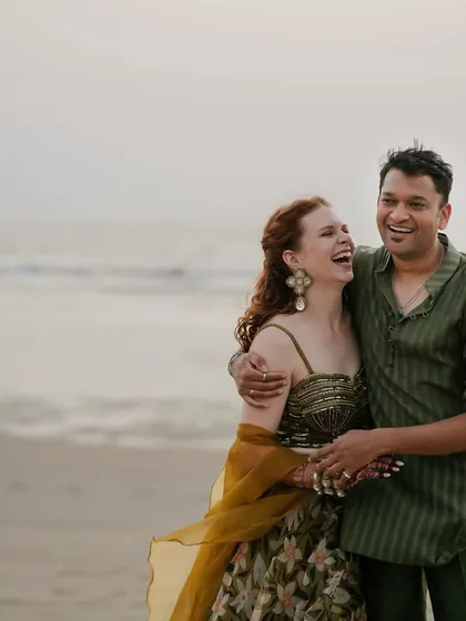 Capturing the easy, breezy vibe of a Goan sundowner. For Rach and Viraj's beach celebration, we chose earthy, tone-on-tone outfits. The bride's look was inspired by nature with a floral organza lehenga, while the groom wore a sheer olive green kurta, creating a relaxed yet chic couple style.