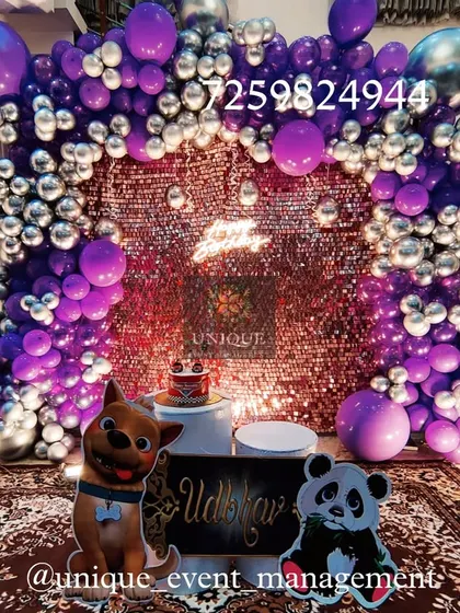 A birthday decoration set up at home with a purple and silver theme. It features a sparkling sequin backdrop, a balloon arch, and cute animal cutouts, showing how we can create a festive party atmosphere in any space.