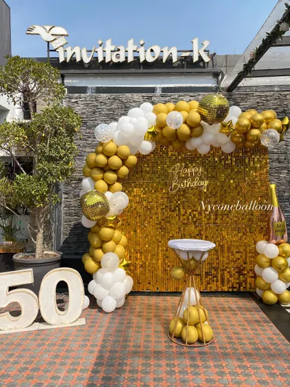 Celebrating a 50th birthday in style with this outdoor setup. I used a brilliant gold sequin wall, a gold and white balloon arch with disco ball accents, and large marquee numbers to mark the golden milestone.