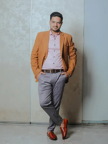 A full-length stylish portrait of the groom leaning against a wall. His confident pose and smart casual attire make for a great shot during the pre-celebration moments.