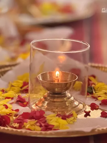 A beautifully lit diya (lamp) on a tray of flowers, prepared for the Ram Tarak Homa. The simple flame represents the eternal light of the Self.