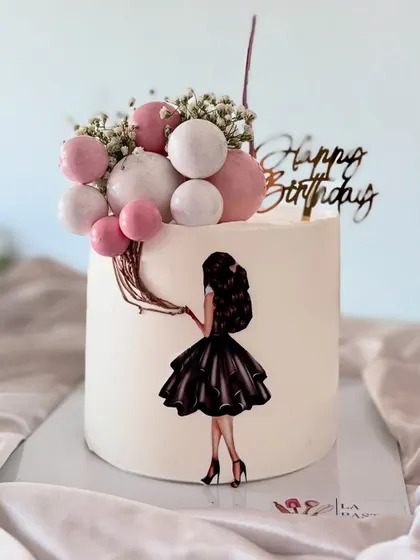 A chic and stylish birthday cake featuring an illustration of a girl holding a bouquet of balloons. The pink and white spheres create a 3D balloon effect.