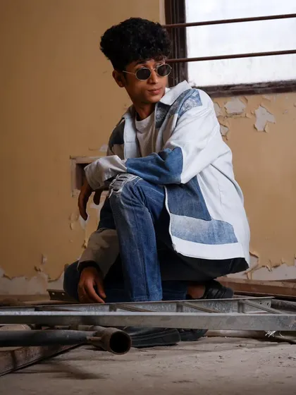 A cool, relaxed portrait of a male model in a deconstructed space. The pose and setting give it an urban, contemporary vibe.