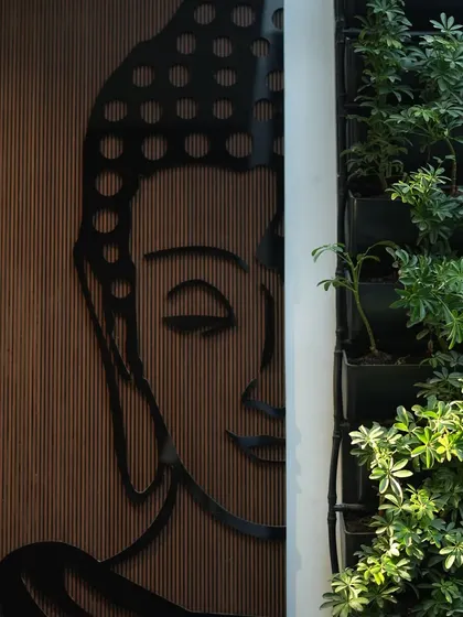 A duplicate image showing the blend of a Buddha wall art piece with a living green wall.
