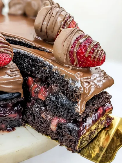 Lifting a slice of our Boozy Nutella Strawberry cake reveals the rum-soaked layers, packed with our homemade strawberry compote.