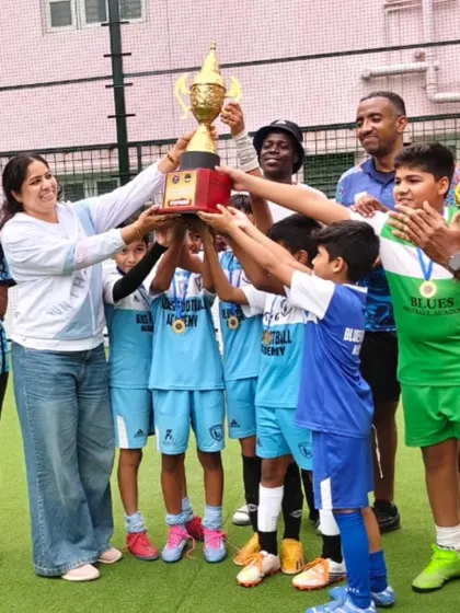 Another angle of our young champions lifting their trophy high. These moments of shared success are what build a strong and supportive team environment.