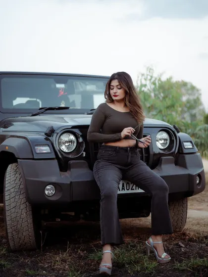 A portrait of a model sitting on the hood of a Thar jeep. This shot combines fashion with a sense of adventure, creating a powerful lifestyle image.