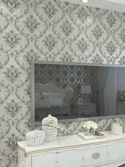 A living room with a grey and white damask wallpaper, creating an elegant and neutral backdrop.