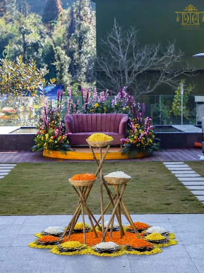 A beautiful Haldi setup with a focus on natural elements and vibrant colors. Baskets of fresh flower petals are arranged in a floral rangoli, creating a stunning and interactive centerpiece for the ceremony.