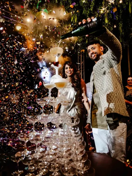 The couple celebrates with a champagne tower, a classic and glamorous touch for a Sangeet or cocktail night.