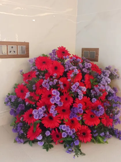 A beautiful bouquet of red and purple flowers, perfect for placing in a corner or on a side table to add a pop of color.
