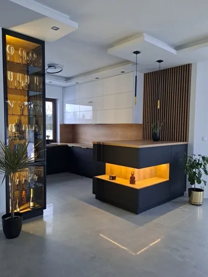 A stunning open-plan kitchen with a large island featuring display shelves. A floor-to-ceiling glass crockery unit and fluted wood panels add layers of texture and luxury.
