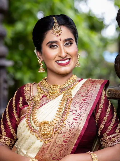 The classic combination of a cream and maroon saree with gold temple jewellery is timeless. This set includes a choker and a Lakshmi pendant haaram, creating an elegant and divine look.