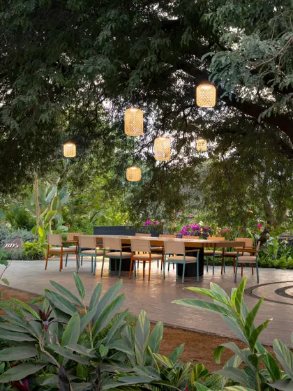 For this outdoor gathering space, we designed a series of custom woven pendant lights. They hang like lanterns from a large tamarind tree, creating a magical and intimate dining experience under the open sky.