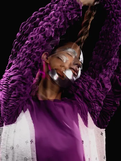 A creative motion shot highlighting the long rope braid and the metallic makeup, giving a sense of otherworldly movement.