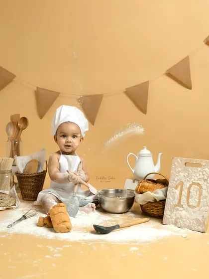 A wider view of the 'Baby Chef' set, complete with a tiny teapot, bread baskets, and a sign marking the baby's 10-month milestone. Every detail is thoughtfully arranged for a perfect shot.