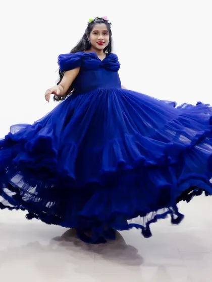 A beautiful photo of a young girl twirling in a royal blue ruffled gown, creating a stunning visual effect.