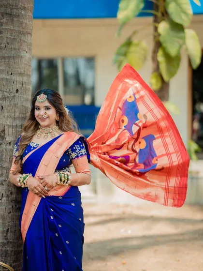 A dynamic shot of a bride, with the pallu of her royal blue Paithani saree flying in the wind.