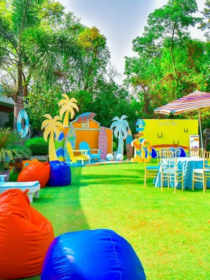 A vibrant summer pool party theme, with colorful bean bags, poolside lounge chairs, and a backdrop of surfboards and palm trees.